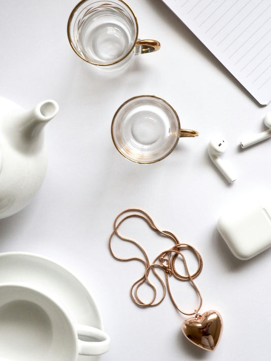 White table with a gold heart necklace and two gold tea cups